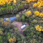 Tiny house surrounded by lush forest and a small pond in rural Queensland.