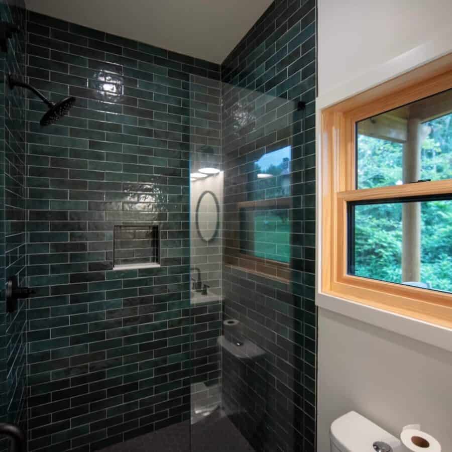 Compact bathroom featuring dark green subway tiles and a modern shower area.
