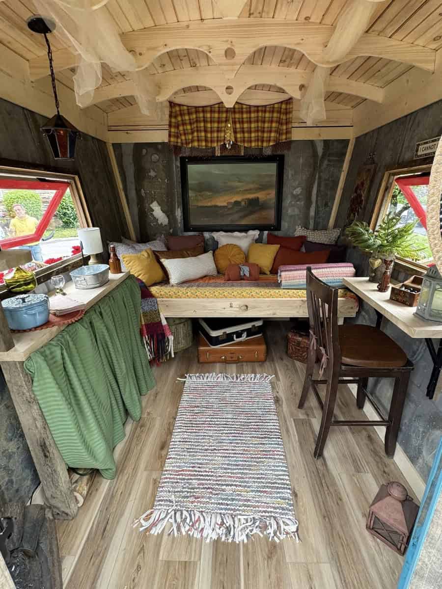 Charming tiny house interior featuring rustic decor, colorful cushions, and large windows with sceni.
