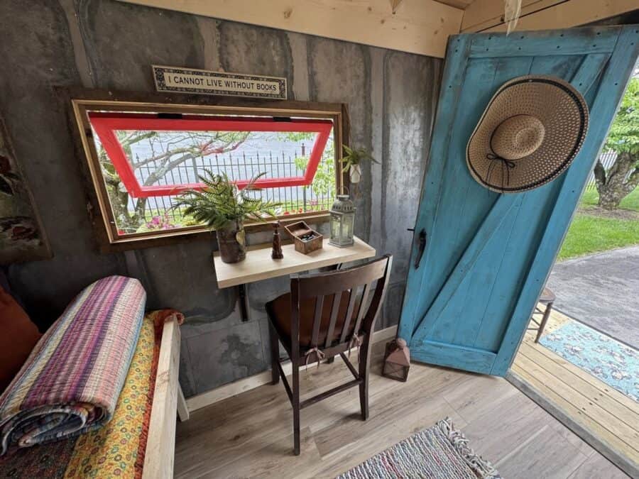 Charming tiny house interior featuring a small desk, window view, and open door to outdoor space.