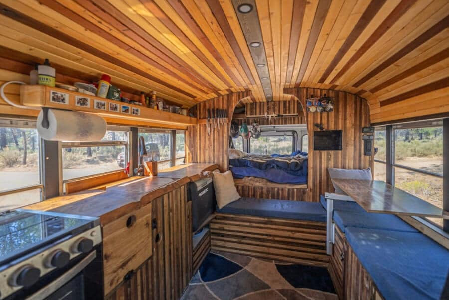 Interior view of a cabin-like skoolie featuring warm wooden walls and ceiling.