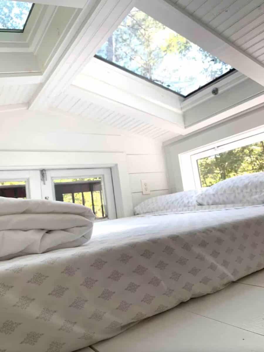 Tiny house bedroom with large skylight and white interior.