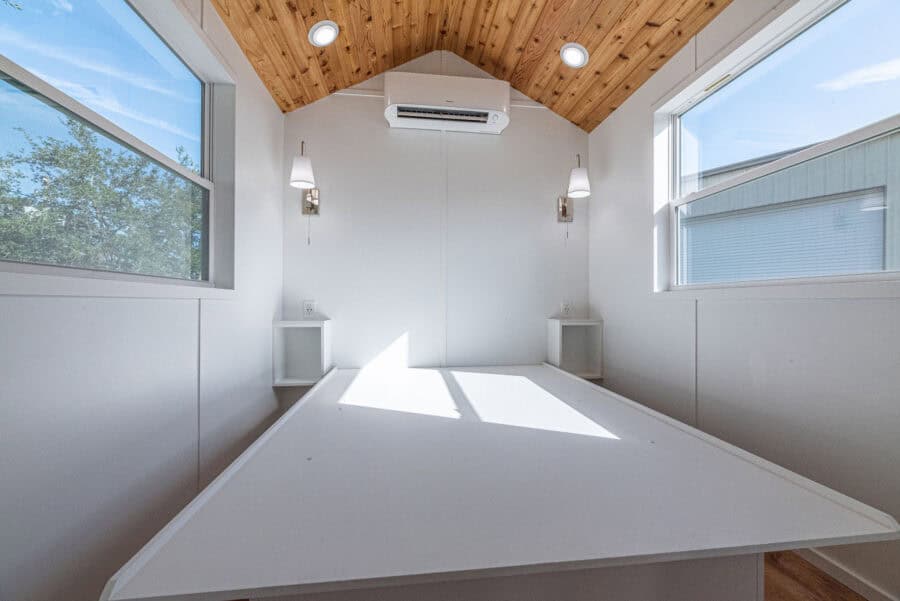 Bright tiny house interior with large windows and wooden ceiling, showcasing a minimalist and functi.