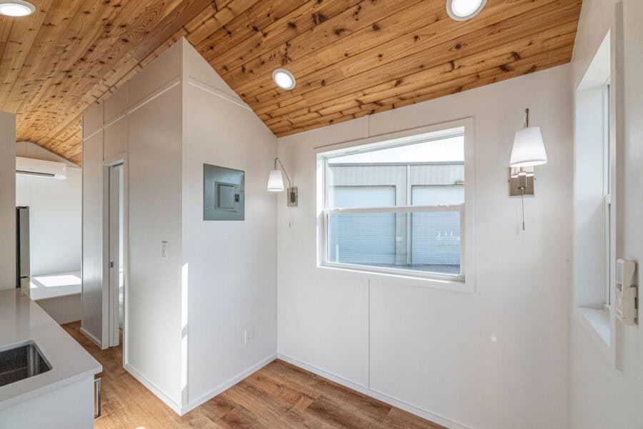 Tiny house interior with wooden ceiling and modern lighting fixtures.