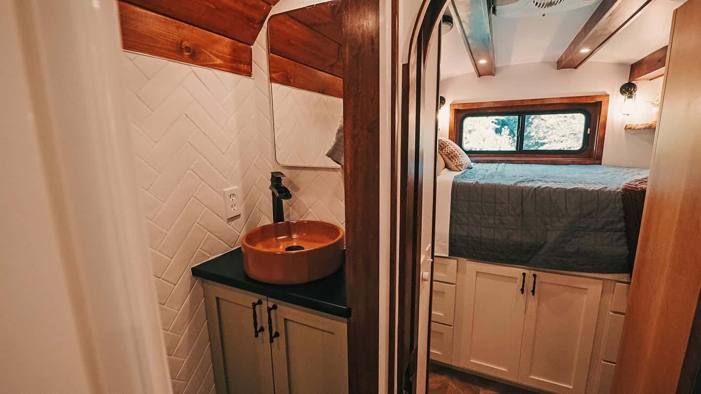 Bathroom vanity with a concrete vessel sink and black counter, looking through to the lofted bedroom