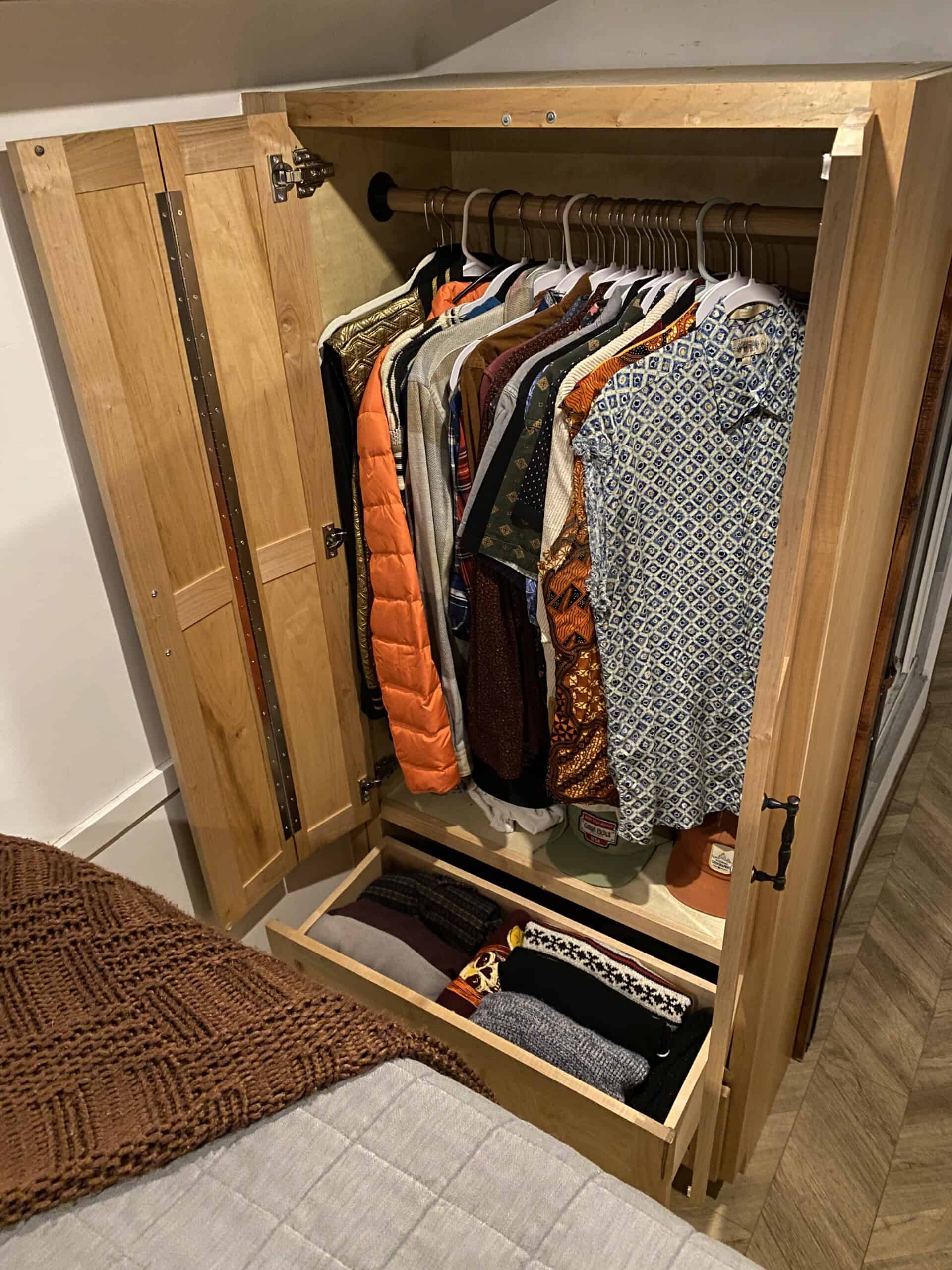 Open wardrobe revealing a full clothes rail and pull-out drawers