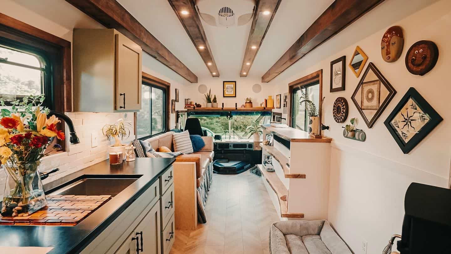 Long interior view showing exposed wood ceiling beams, arched openings, and chevron vinyl-plank flooring
