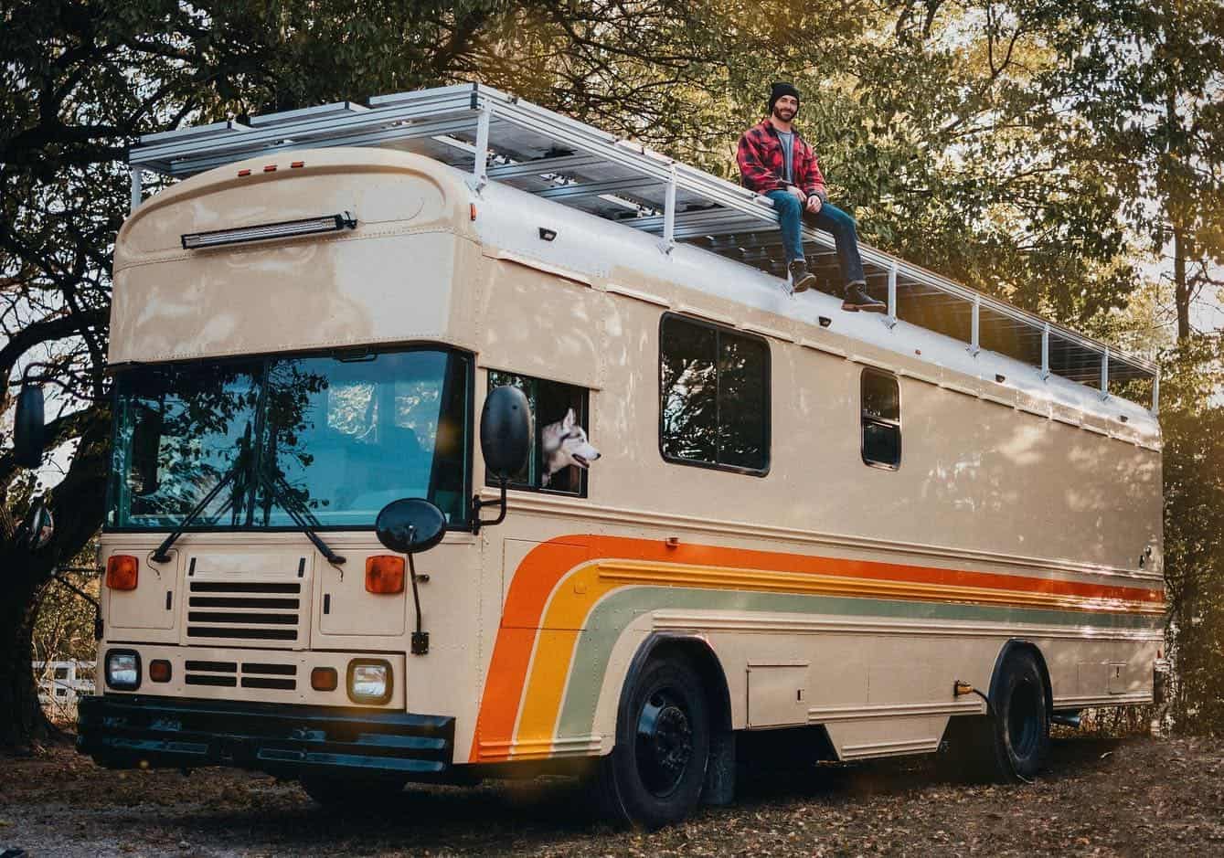 36-foot Bluebird school bus conversion with raised roof, rooftop solar, and a retro orange exterior stripe