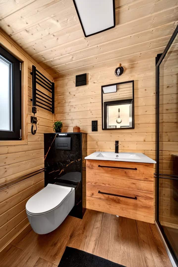 Justine bathroom with a wood-and-marble vanity, backlit mirror, and towel radiator