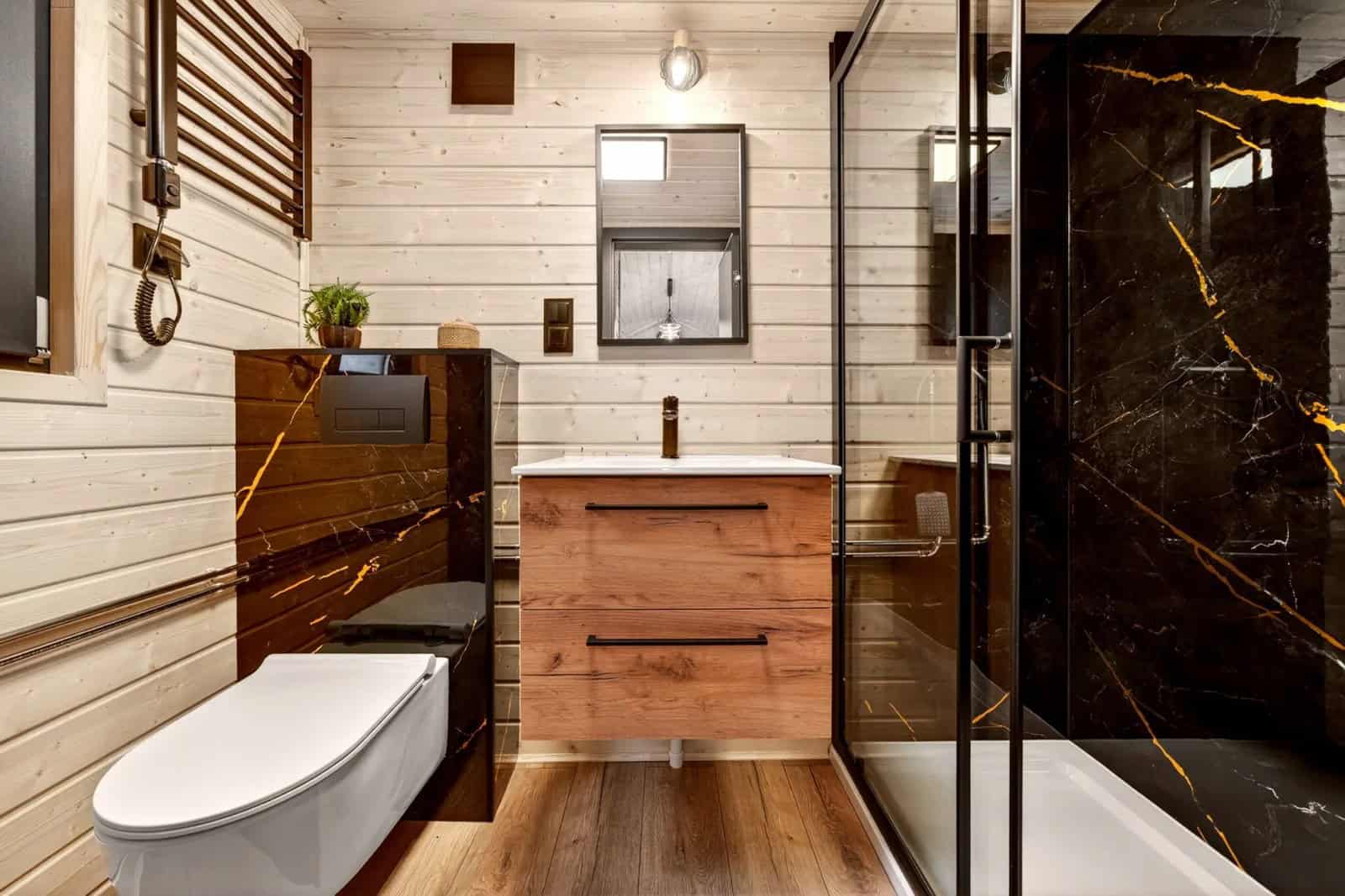 Bathroom in the Justine with a black-marble vanity, wall-hung toilet, and a glass walk-in shower