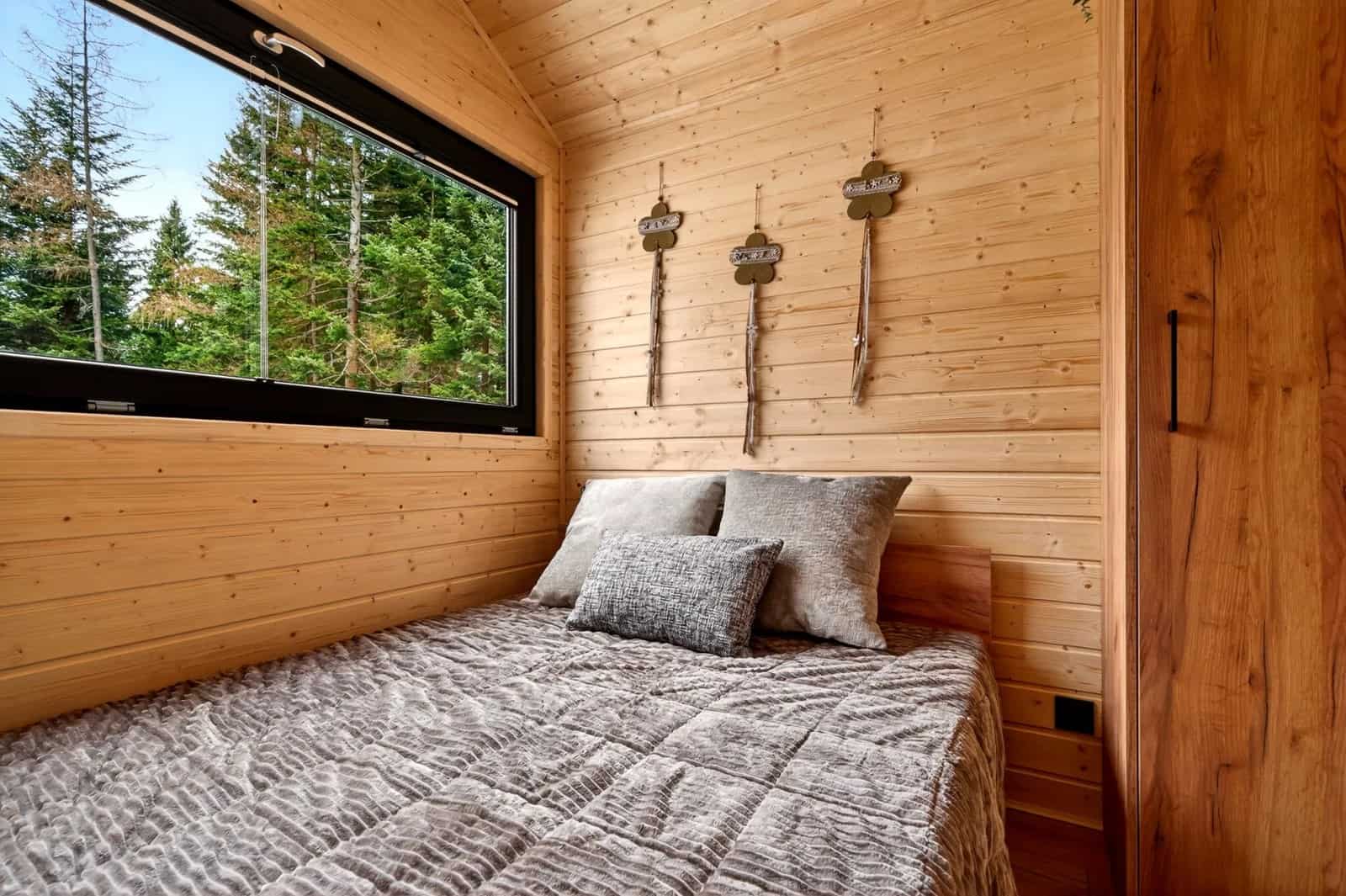 Bedroom in the Justine with a double bed, a large window, and a wood wardrobe