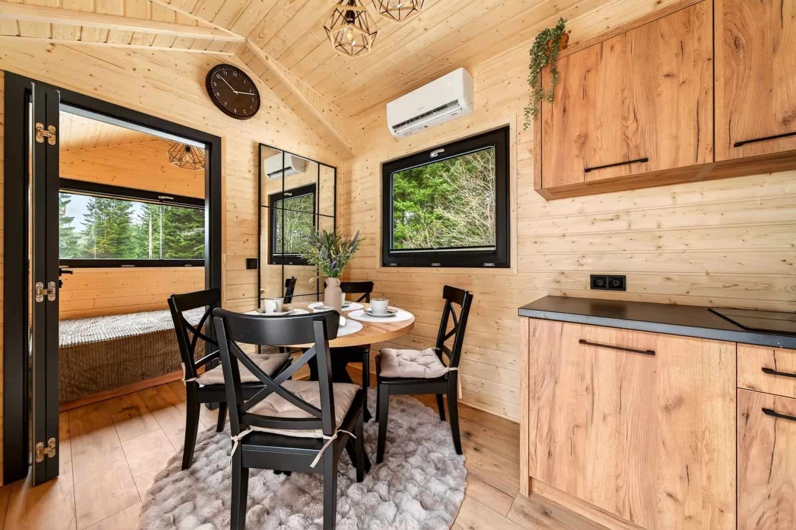 Dining nook in the Justine with black cross-back chairs beside a forest-view window