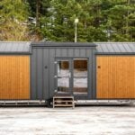The Justine tiny house by Craft House with thermo-pine siding and a charcoal standing-seam gable roof in a snowy forest