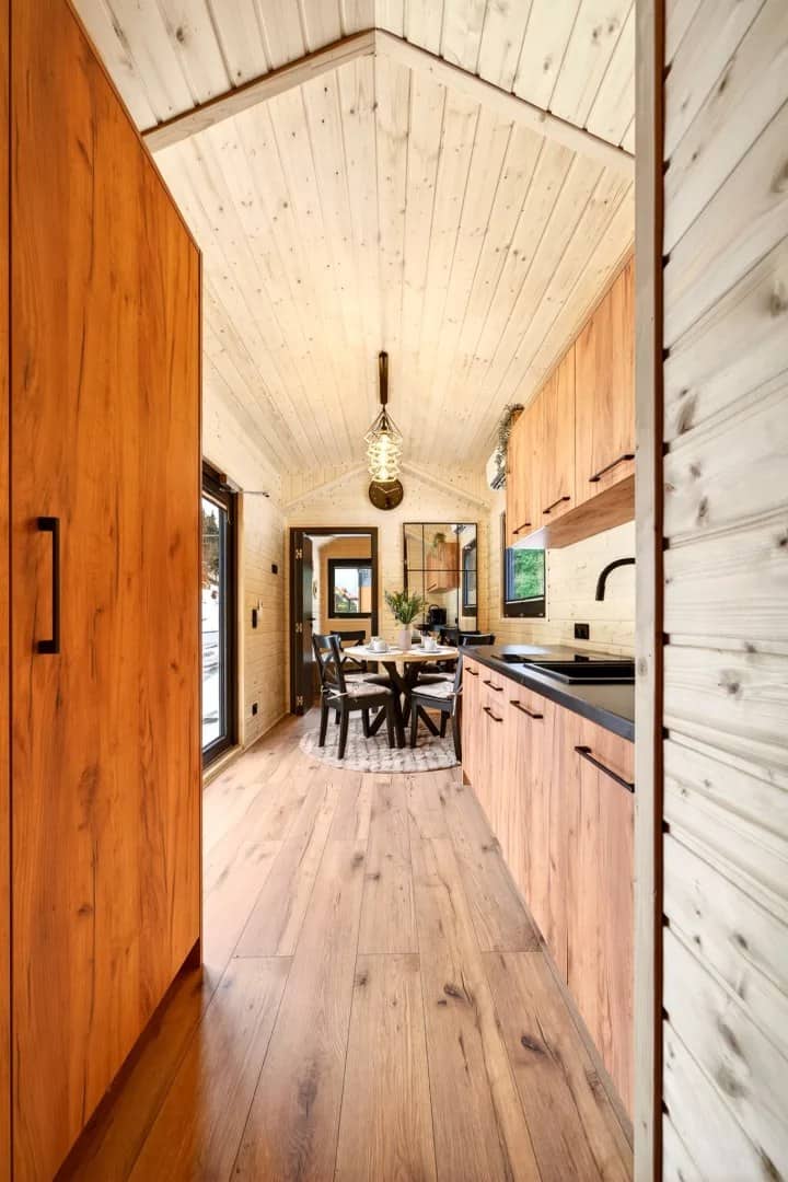 Looking down the length of the Justine with the galley kitchen and round dining table under a gable ceiling