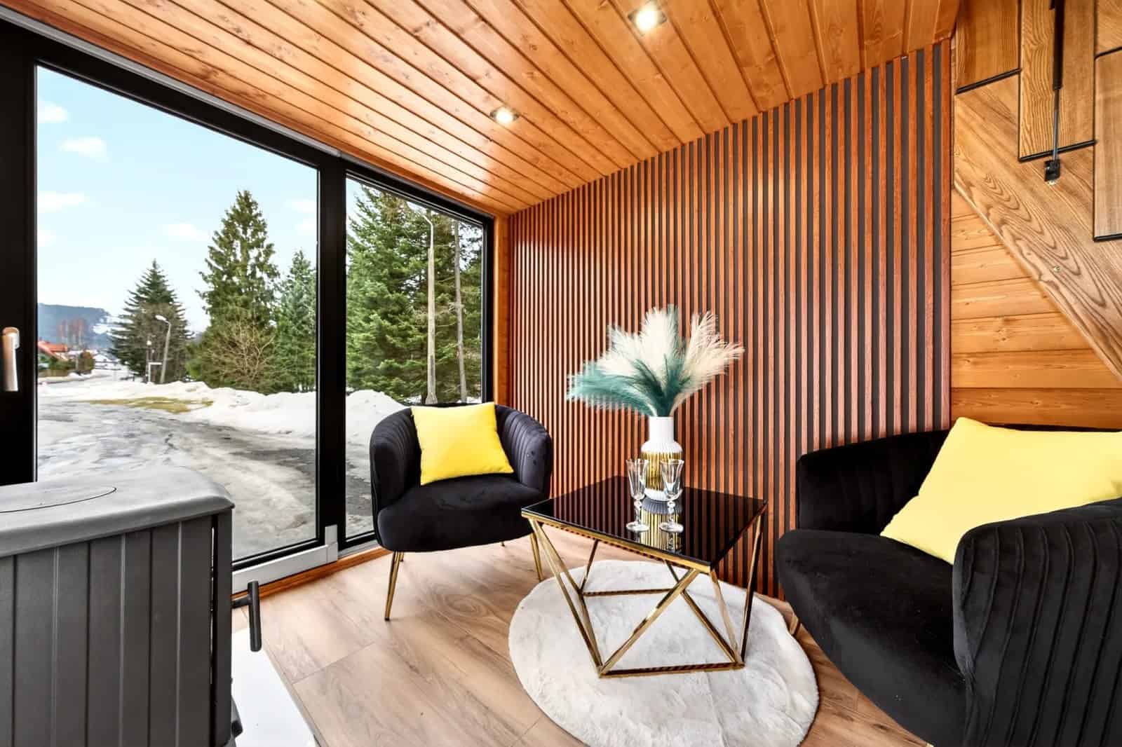 Katrin living room with black velvet armchairs, a gold-and-glass table, and a wood-burning stove by the windows