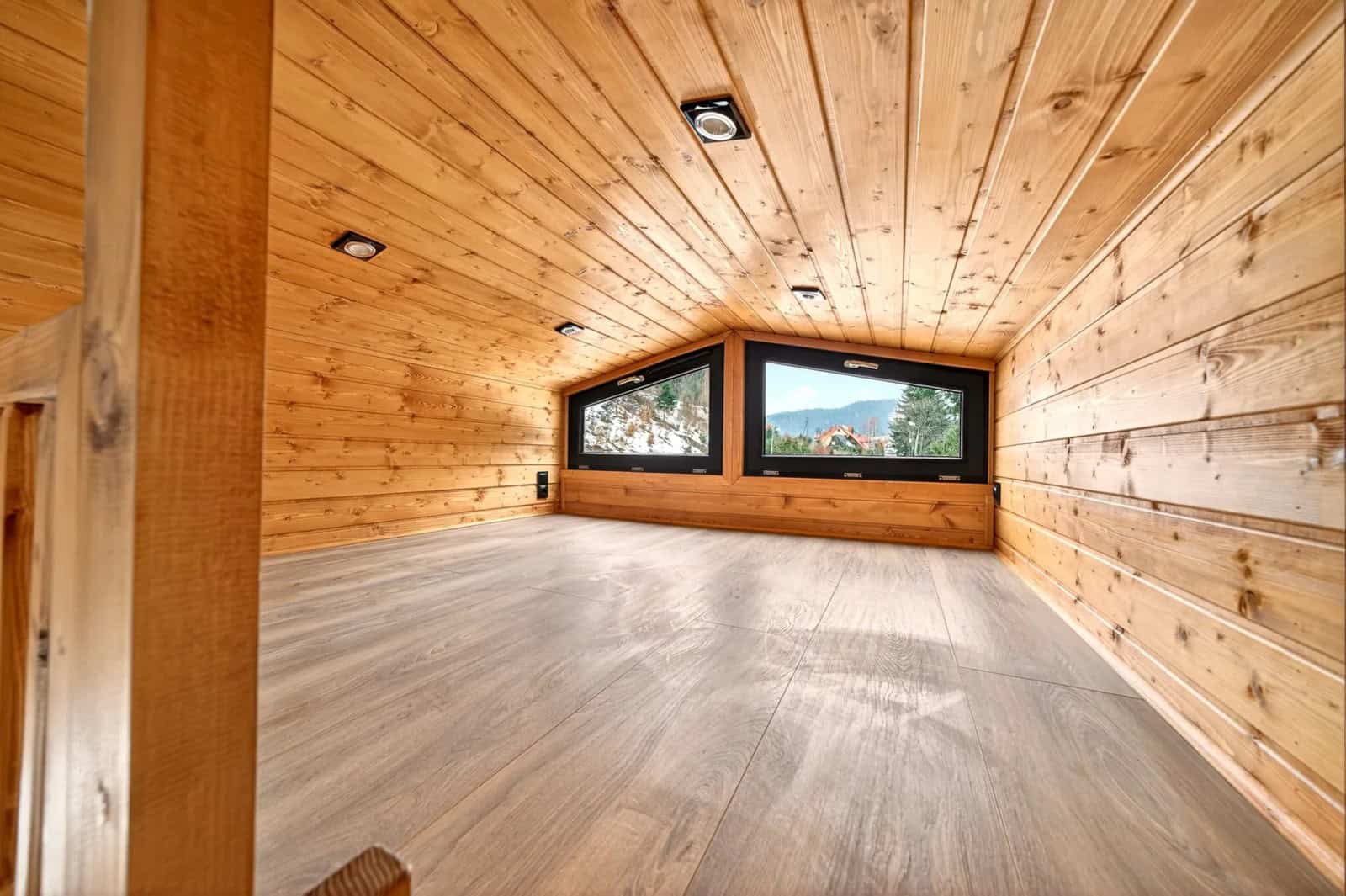 Mezzanine bedroom in the Katrin with a double bed under the gable and windows to the forest
