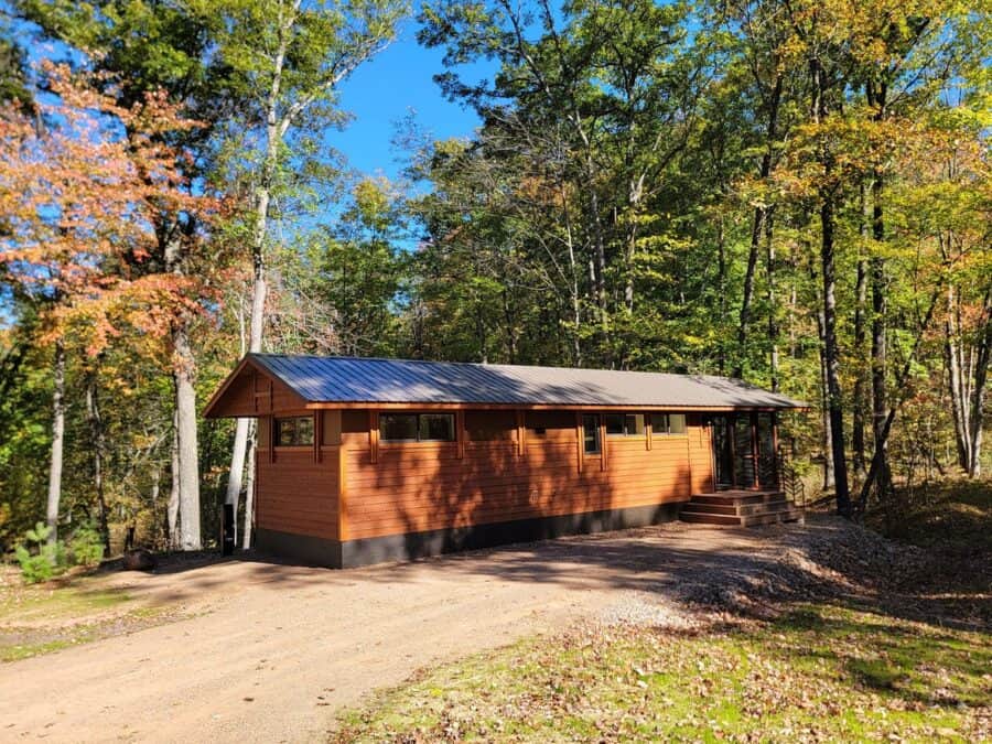 Tiny house with wooden exterior in a forest setting.