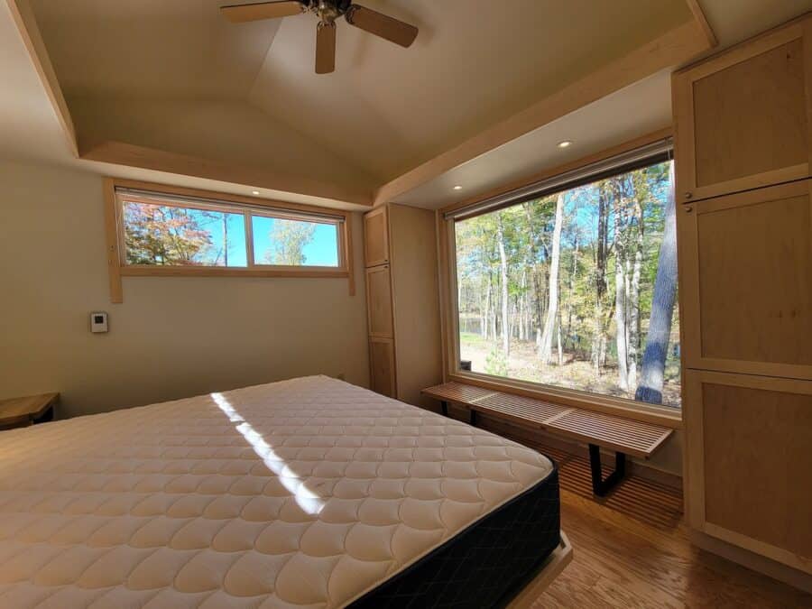 Enlarged king bedroom with floor-to-ceiling glass windows overlooking the lake