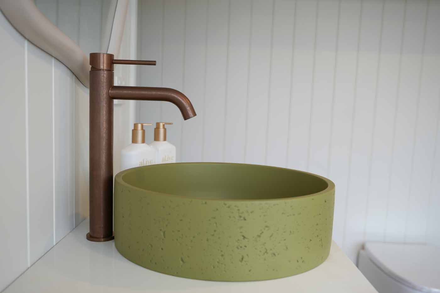 Close-up of the olive green concrete basin and copper tap in the Kookaburra 2.0 bathroom