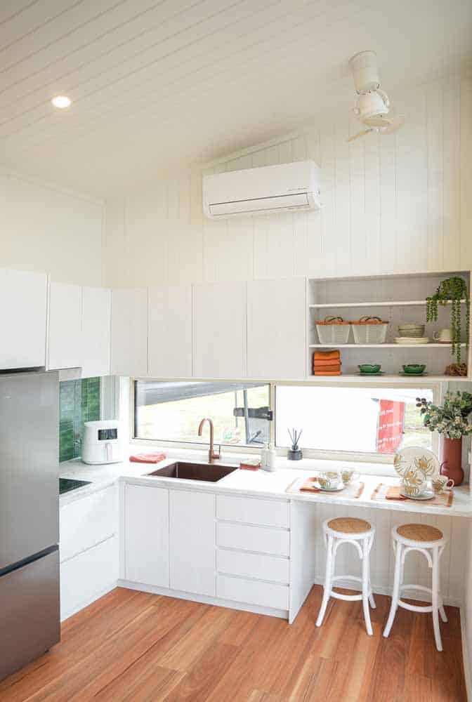 L-shaped kitchen in the Kookaburra 2.0 with white cabinetry, stone benchtops, and overhead storage