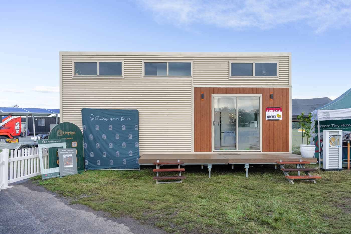 Front exterior of the Kookaburra 2.0 tiny house with cream corrugated cladding and a timber entry wall