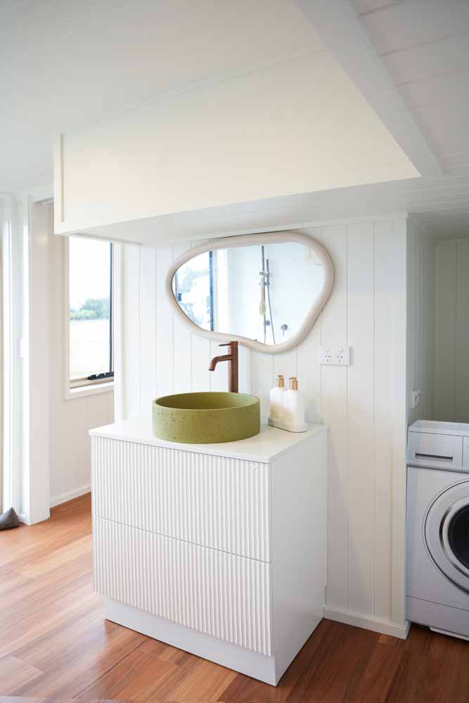 Fluted vanity with a green concrete basin next to the front-load washing machine in the Kookaburra 2.0