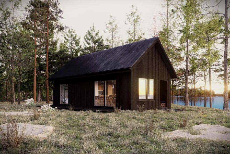 Tiny house with black exterior in a forested area at sunset.