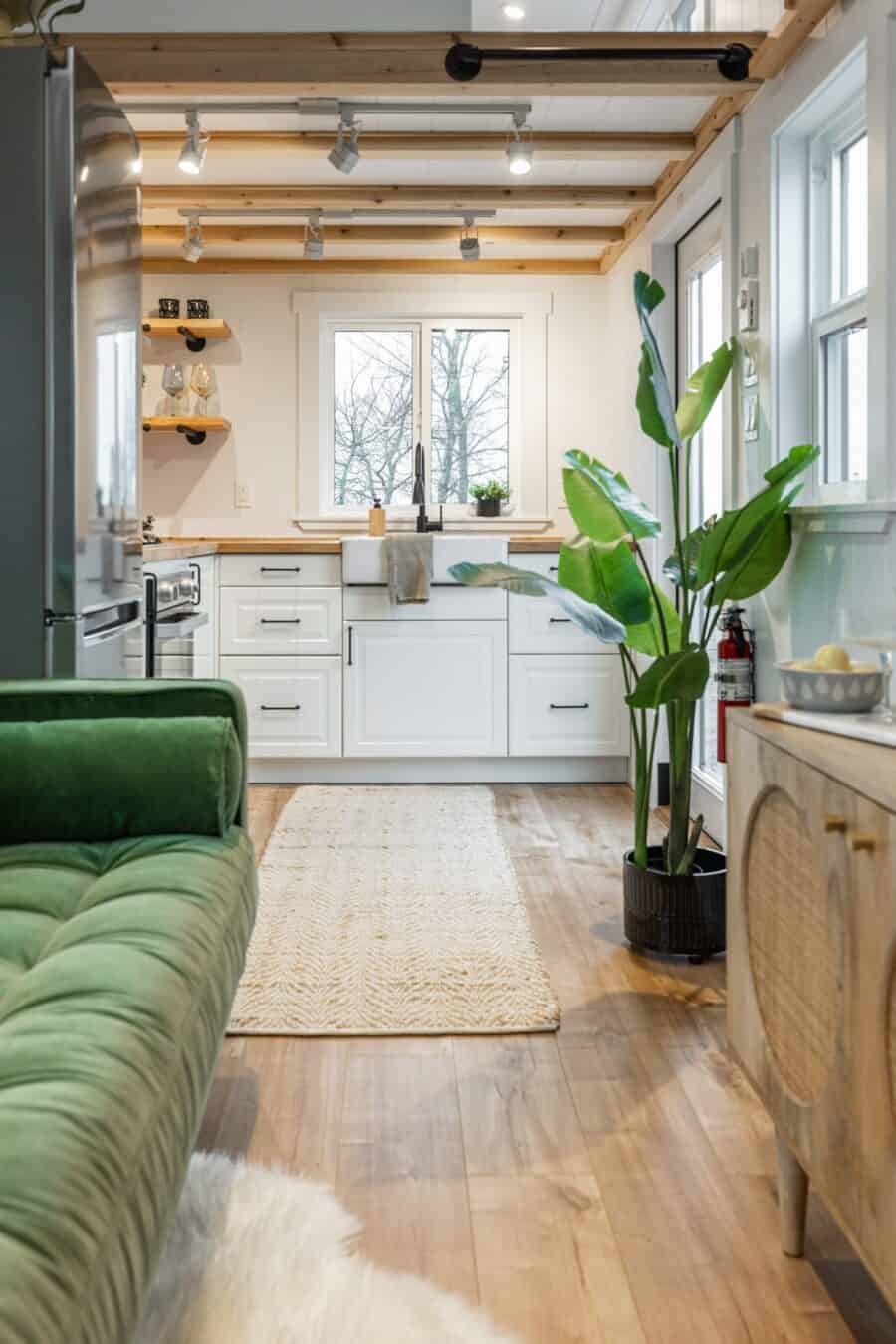 Bright tiny house kitchen with white cabinets and natural wood accents.