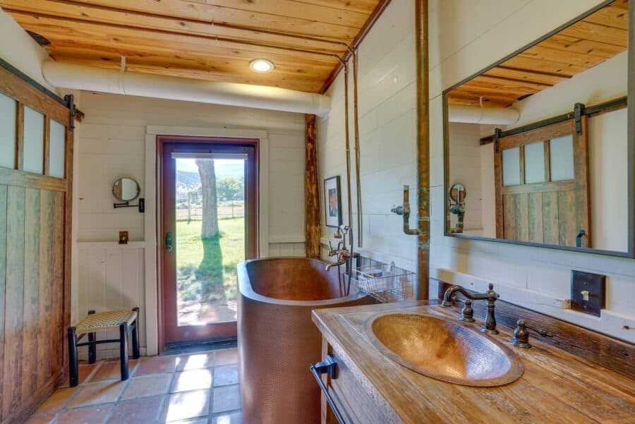 Cozy log cabin bathroom featuring a copper bathtub and rustic wooden accents.