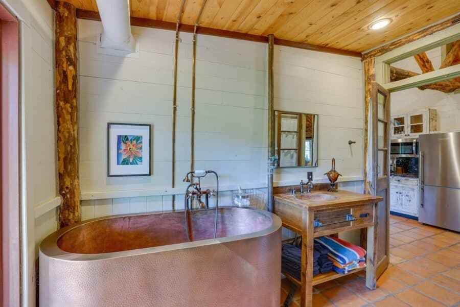 Rustic log cabin bathroom featuring a copper soaking tub and stone details, blending natural materia.