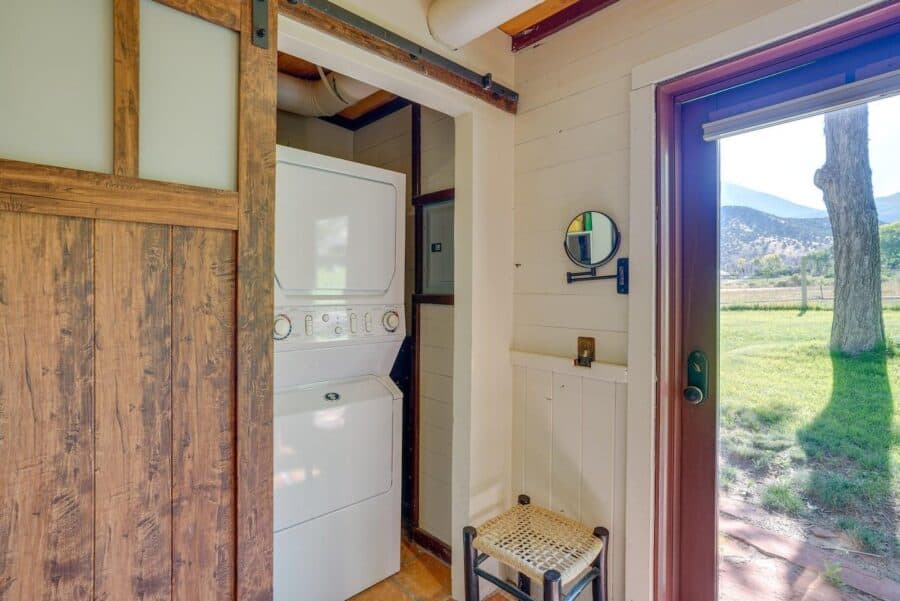 Compact laundry nook inside a rustic log cabin with stone accents, featuring a stacked washer and dr.