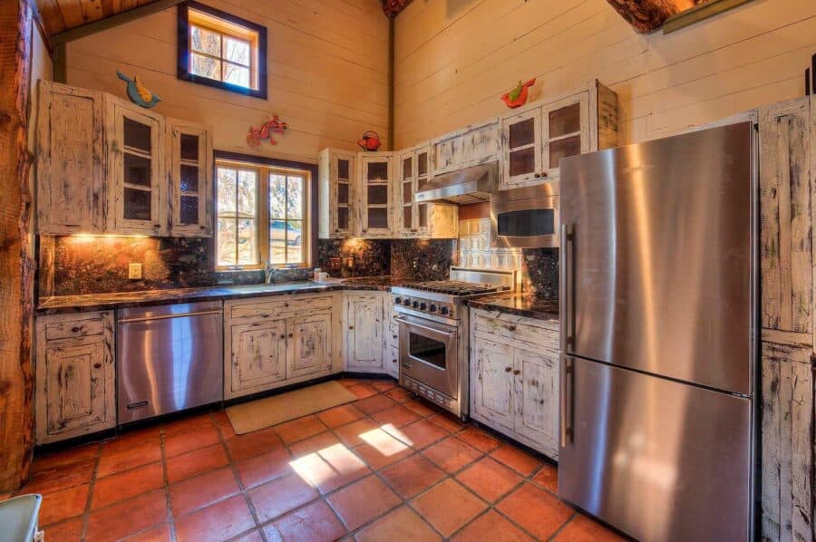 Charming log cabin kitchen featuring rustic wood cabinets, stone details, and modern appliances in U.