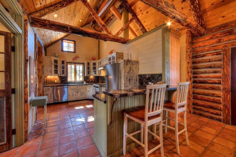 Rustic log cabin kitchen with stone accents and wooden beams.