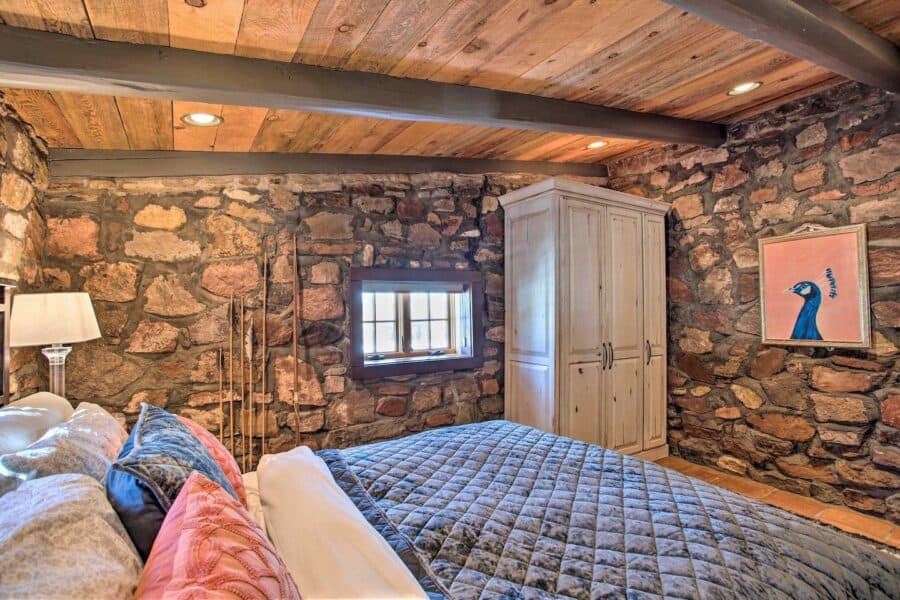Charming log cabin bedroom featuring rustic stone walls and wooden ceiling, perfect for small space.