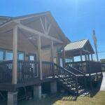 Porch and ramp leading to a cozy tiny house under a bright blue sky.