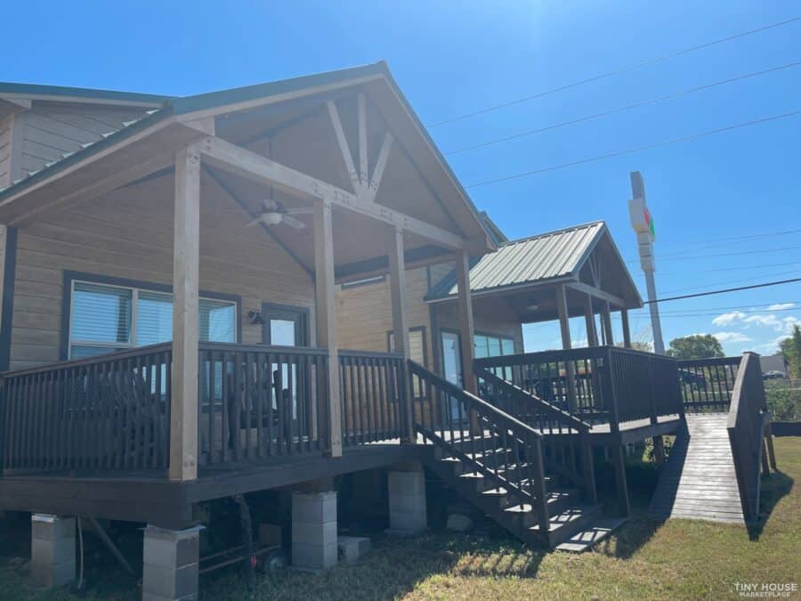 Porch and ramp leading to a cozy tiny house under a bright blue sky.