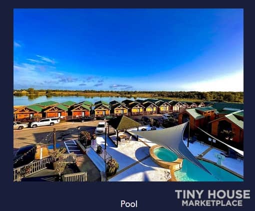 Aerial view of tiny houses surrounding a pool in a small community setting.