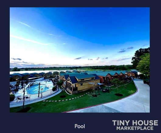 Pool area at a tiny house community with small homes and lush greenery.
