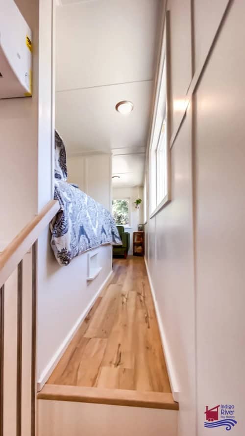 Narrow hallway inside a tiny house with light-colored walls and wooden flooring.