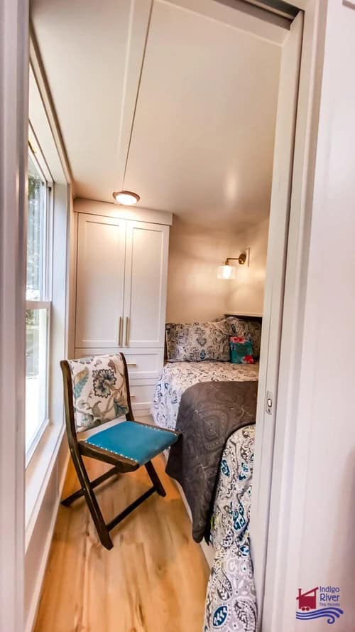 Small bedroom in a tiny house with a bed, window, and a desk for work or study.