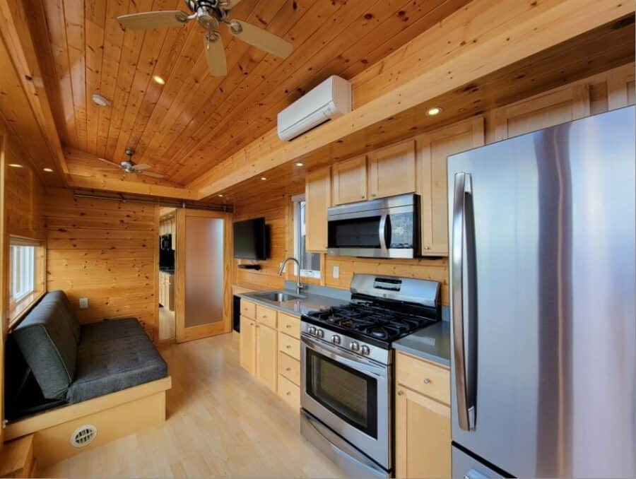 Modern tiny house kitchen with stainless steel appliances and wooden interior design.