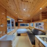 Bright, compact tiny house with wooden accents and large windows.