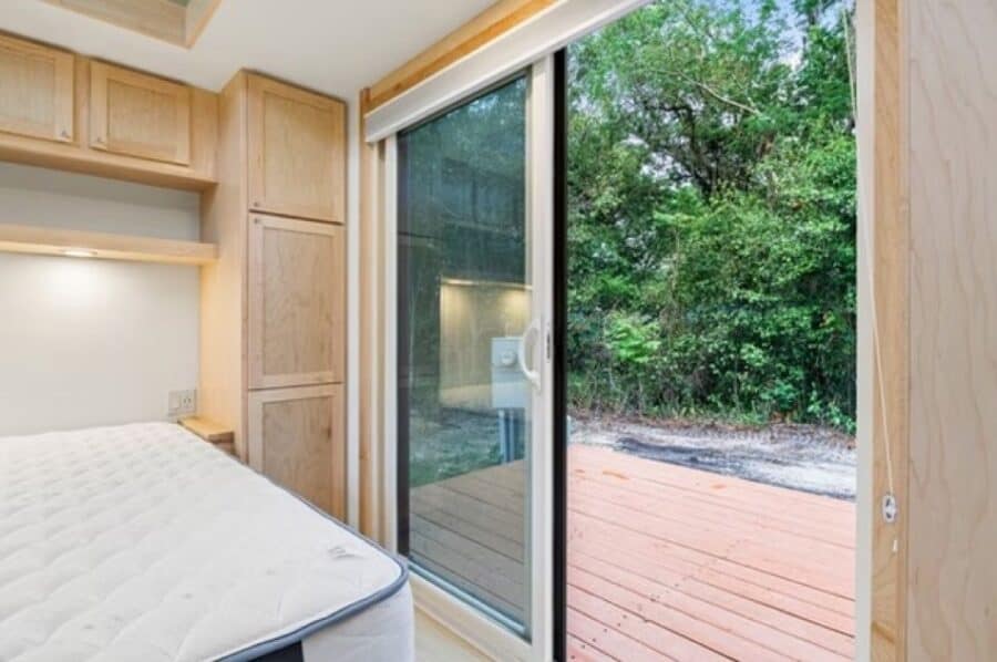 Cozy tiny house interior with large sliding glass door overlooking nature.