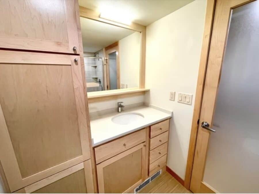 Cozy tiny house bathroom with wooden cabinetry and modern fixtures.