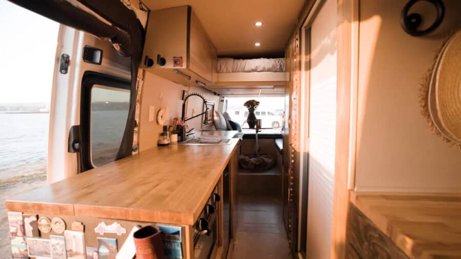 Cozy tiny house interior with water view, compact kitchen, and natural light.