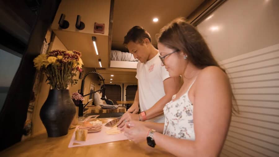 Woman and man cooking together in a cozy tiny house kitchen, embracing small space living.