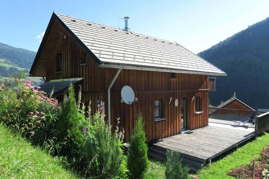 Cozy wooden chalet in Austria surrounded by lush greenery and mountain views.