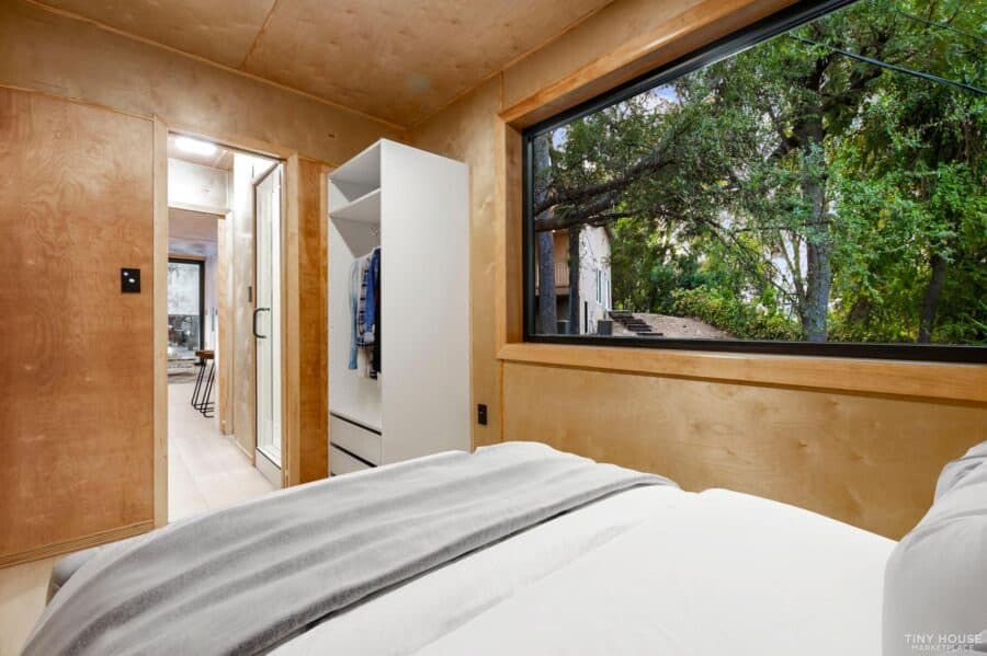 Cozy tiny house bedroom with large window and minimalist design.