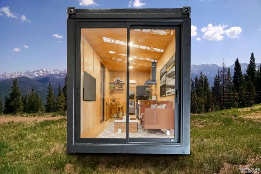 Compact shipping container house with cozy interior and large glass windows in a natural outdoor set.