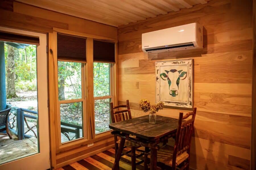 Charming cabin interior with wooden walls, a small dining area, and scenic forest views in Mentone,.